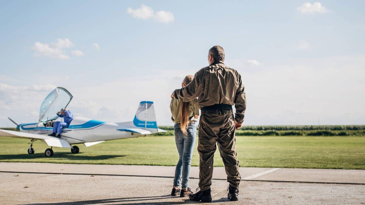 Father and daughter at airfield looking at plane